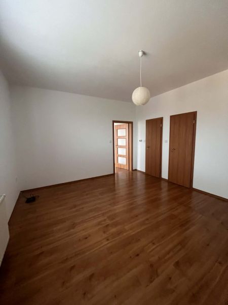A room in a 3-room apartment with white walls and a floor with a wooden decor.