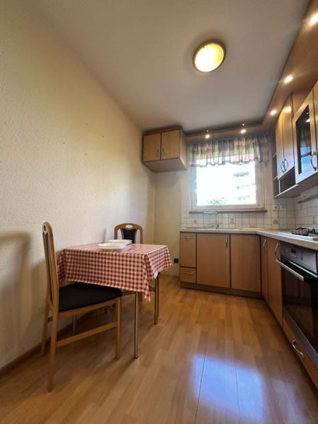 A kitchen in a 3-room apartment with a wooden decor floor and a dining table.