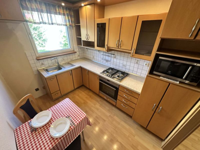 A kitchen with a wooden decor floor and a dining table in a three-room apartment.
