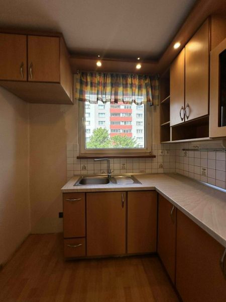 A kitchen with a wood-patterned floor in a 3-room apartment, simple kitchen cabinets.