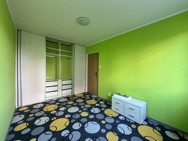 A room in a 3-room apartment with a colorful carpet, green walls, and a built-in wardrobe.