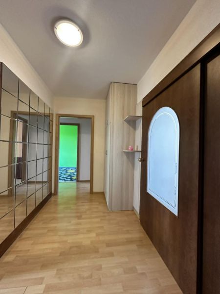 A hallway in a 3-room apartment with a wooden decor floor and built-in wardrobes.