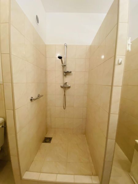A shower corner with tiles in a studio apartment.