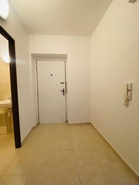 Entrance hall with tiles in a studio apartment, simple white walls and doors.