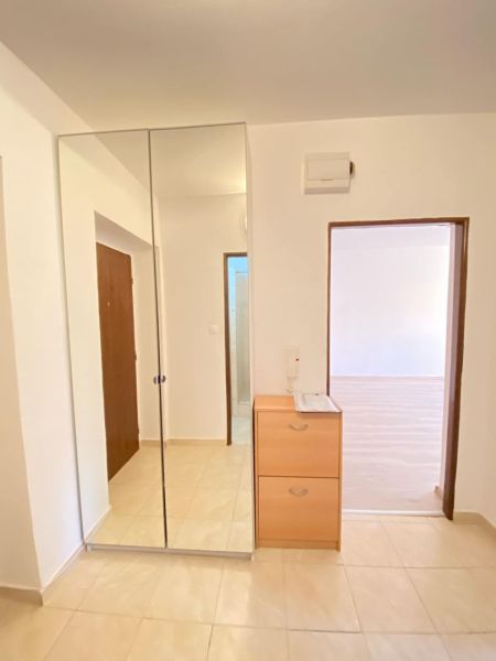 A mirrored wardrobe and a chest of drawers in the entrance area of a studio apartment with a tiled floor.