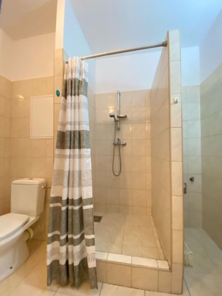 Bathroom in a studio apartment with a bathtub, tiles, and a curtain.