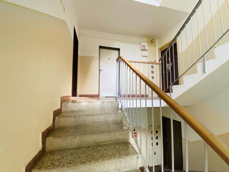 A staircase in a block of flats with a metal railing, leading to the apartments on the floor.