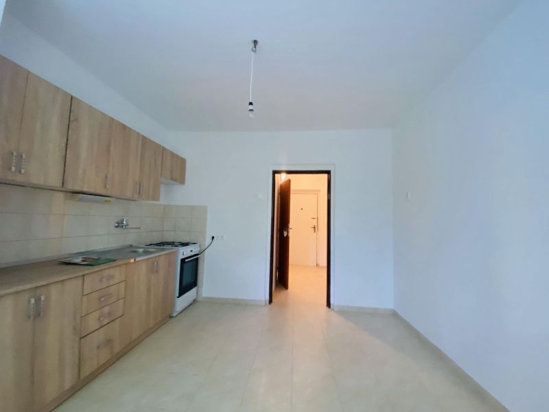 A kitchen in a one-room apartment with a kitchen unit and light walls.