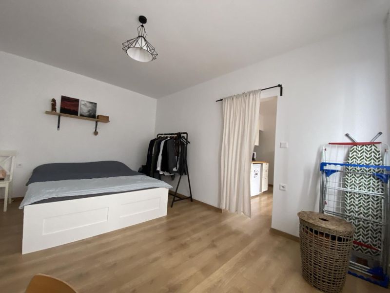 A bedroom in a studio apartment with a bed and a wooden decor floor.