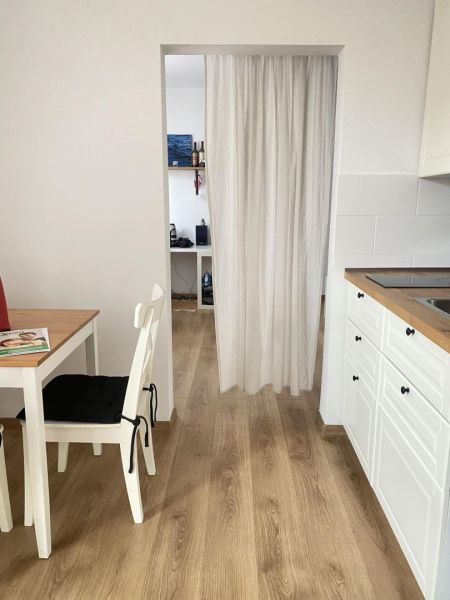 Kitchen corner with a curtain, dining table, and floor with wood decor in a studio apartment.