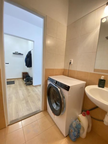 Bathroom in a studio apartment with a washing machine, next to a floor with a wooden decor.