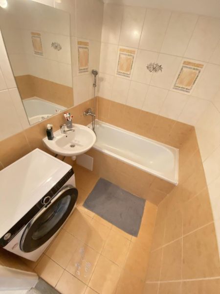 Bathroom with a shower, washing machine, and sink in a studio apartment.