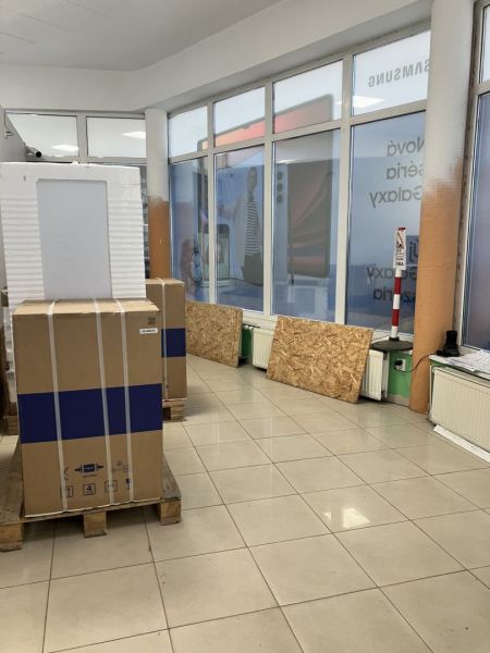 Pallet packaging in commercial premises, light tiles, shop windows with advertising banner.