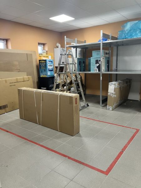 Interior of commercial spaces with shelves, a ladder, and packed boxes for storage.