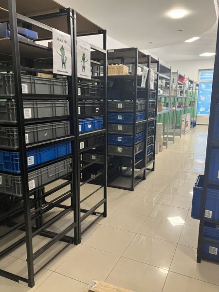 Storage racks with plastic boxes in commercial spaces with tiled flooring.