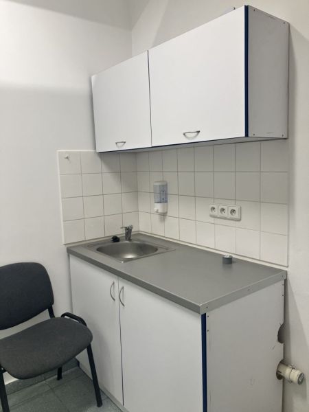 Kitchen corner in commercial premises with white cabinets and a sink.