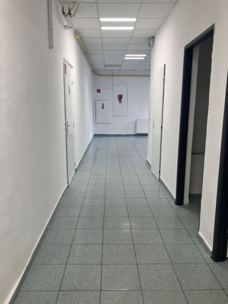 A corridor in commercial premises with white walls and a tiled floor.