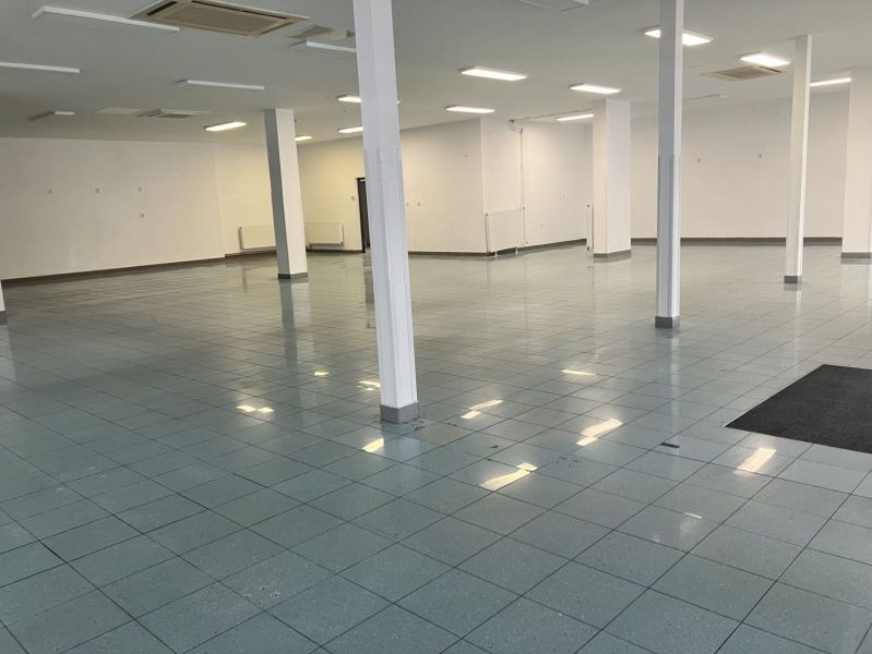 Spacious commercial premises with tiles and columns, ideal for various uses.