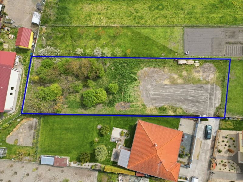 A grassy plot in Horná Potôň suitable for living, surrounded by neighboring plots and buildings.