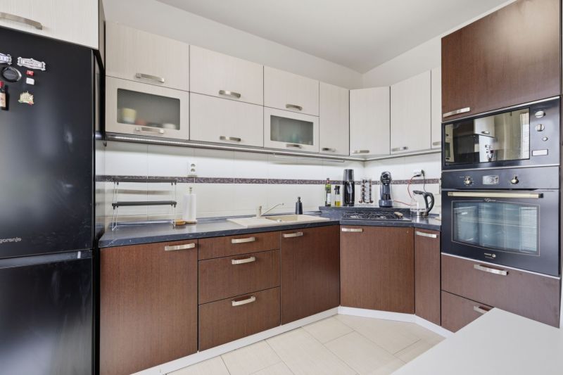 A kitchen in a 3-room apartment with dark furniture and built-in appliances.