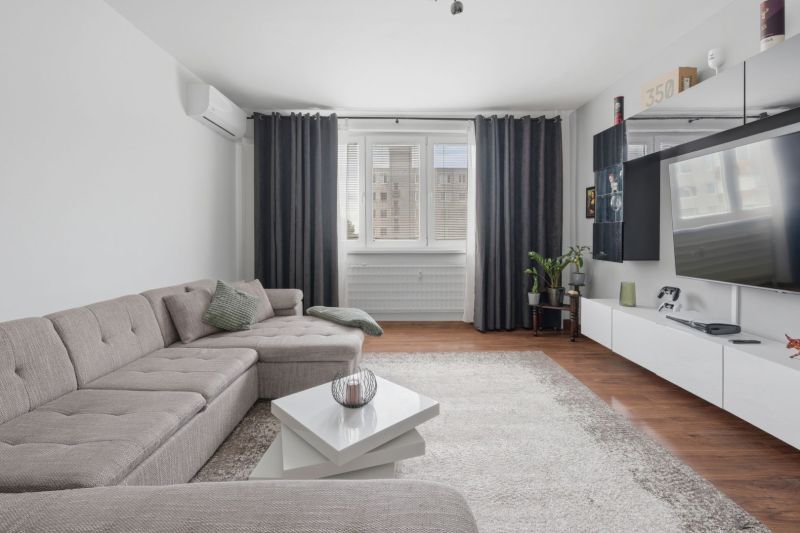 Living room in a three-room apartment with a comfortable sofa and a floor with a wooden decor.