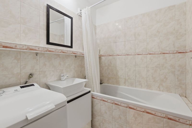 Bathroom with a bathtub, sink, and washing machine in a 3-room apartment.