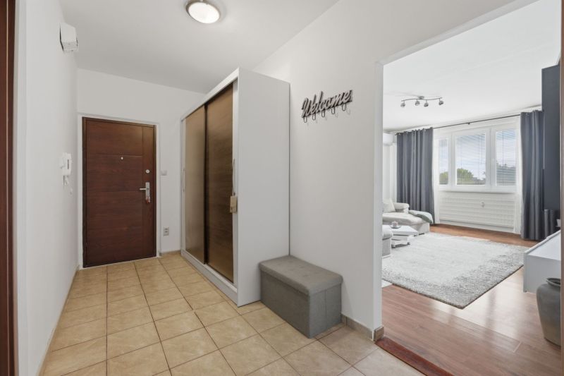 Entrance hallway with tiles, wardrobes, leads to a living room with a wooden decor floor.
