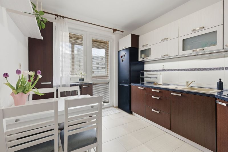 A kitchen in a 3-room apartment with dark furniture and a dining table.