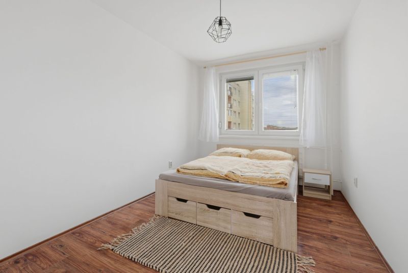 Bedroom in a 3-room apartment with wood-patterned flooring, a bed, and a rug.