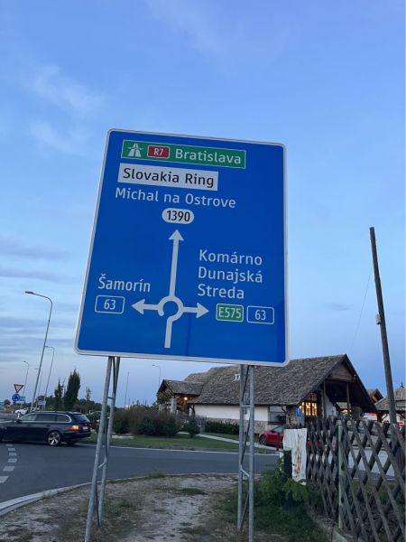A road sign in Holice shows the direction to Slovakia Ring and cities like Šamorín, Komárno.