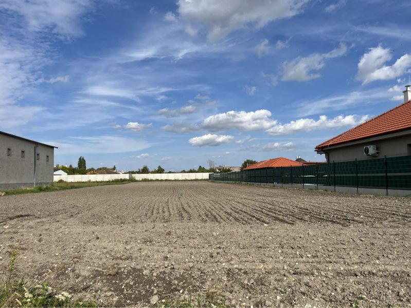 Plots - housing in Holice, between houses with red roofs and blue sky.