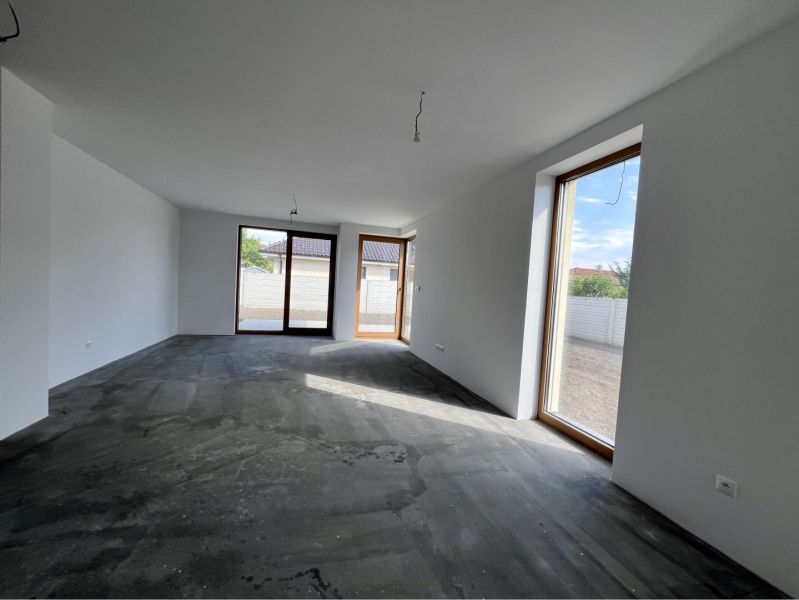 A spacious room with a concrete floor and large windows in a family house.