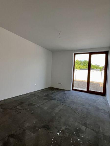 Empty room with a concrete floor and glass doors in a family house.