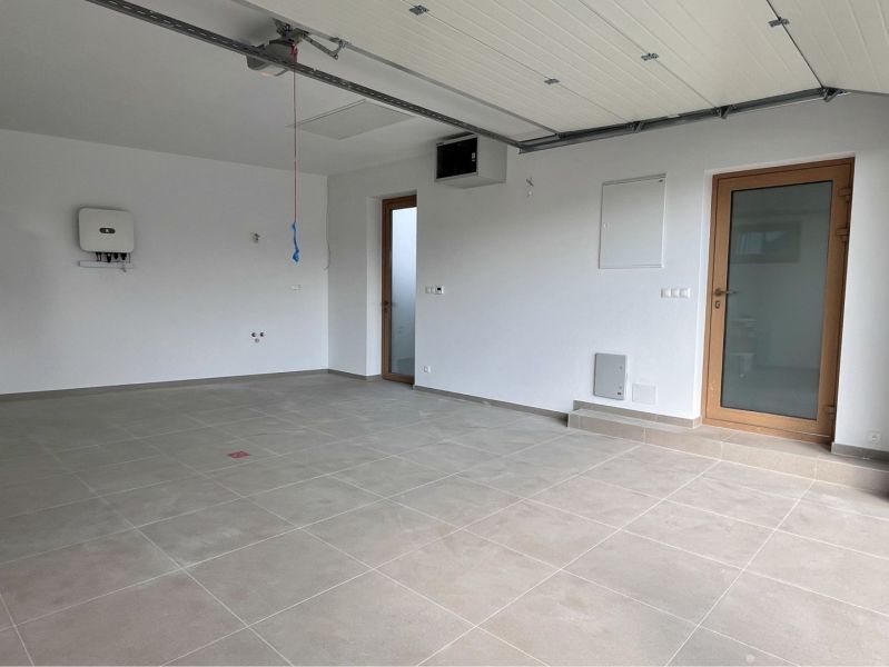 A garage in a family house with a tiled floor and white walls.