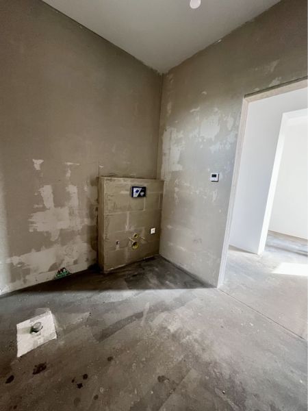 The interior of a family house with plastered walls and a floor awaiting finishing.