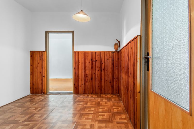 A hallway in a 3-room apartment with a wooden decor floor and wooden wall paneling.