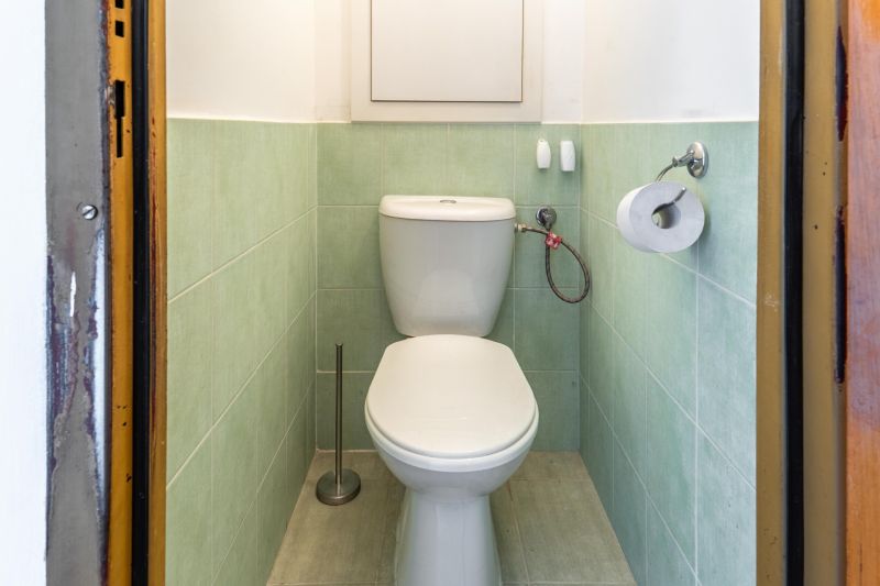 A toilet with green tiles in a 3-room apartment.