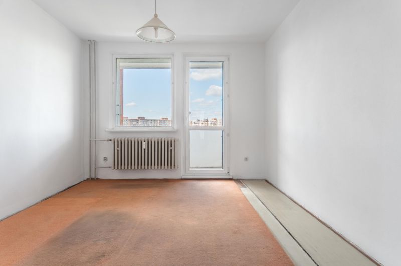 Empty room in a 3-room apartment with a window and a radiator.