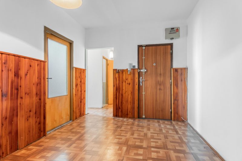 A hallway of a 3-room apartment with wooden paneling and a floor with a wooden decor.
