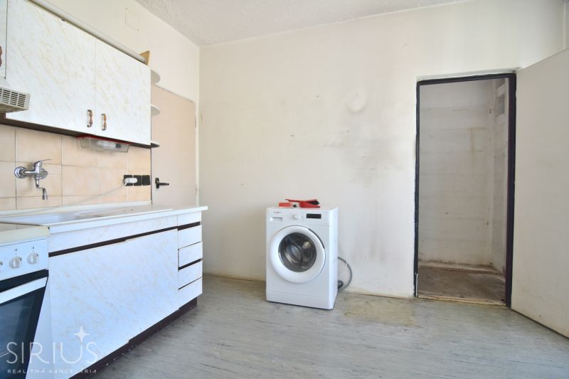 A kitchen in a 3-room apartment with a washing machine and a kitchen unit.