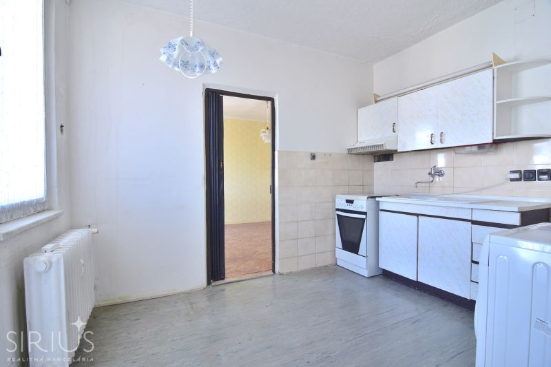 A kitchen in a 3-room apartment with a white kitchen unit and a combination stove.