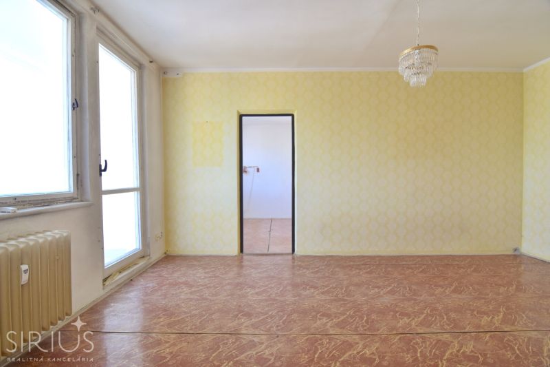 A room in a 3-room apartment with large windows, a chandelier, and a floor with a wooden decor.