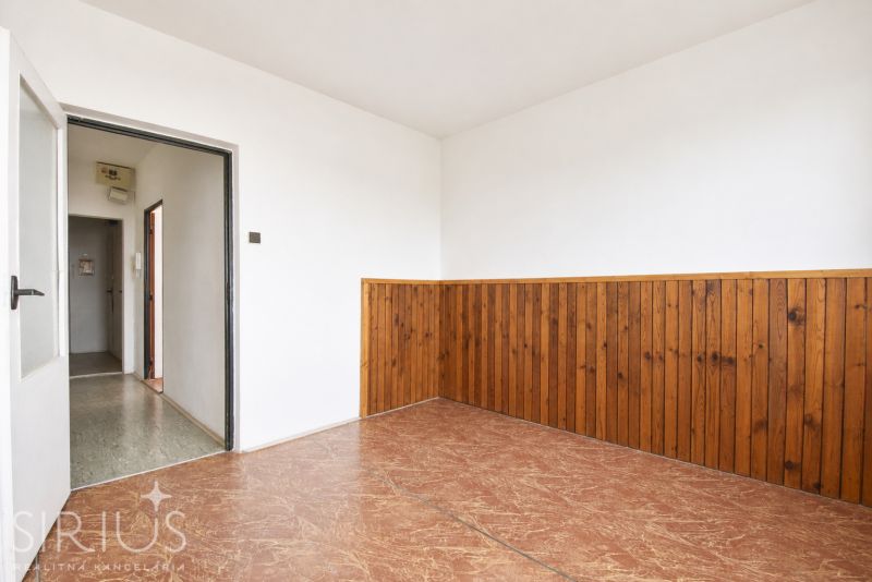 A white room in a 3-room apartment with paneling and wood imitation on the floor.