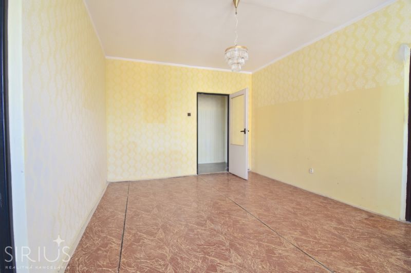 A room with wallpaper and a chandelier in a 3-room apartment, with a wooden decor floor.