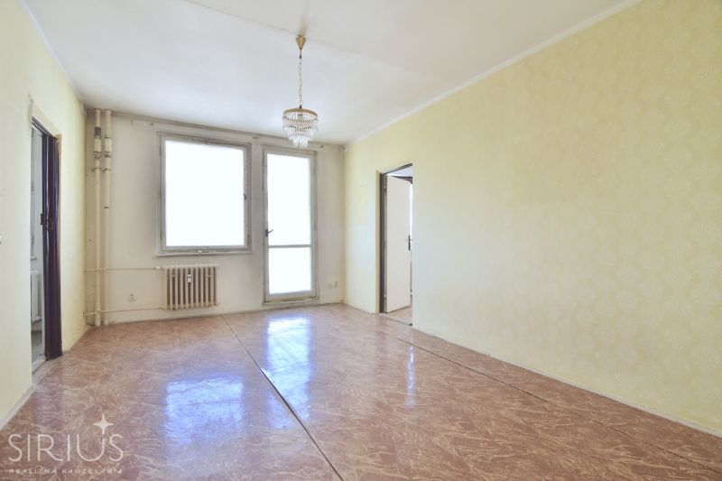 Bright living room in a 3-room apartment with a chandelier and wood-patterned flooring.