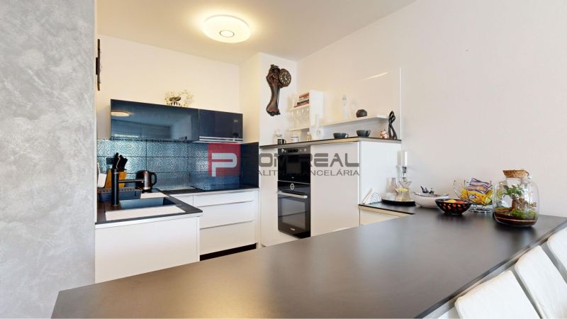 A kitchen in a 2-room apartment with built-in appliances and decorative wall clocks.