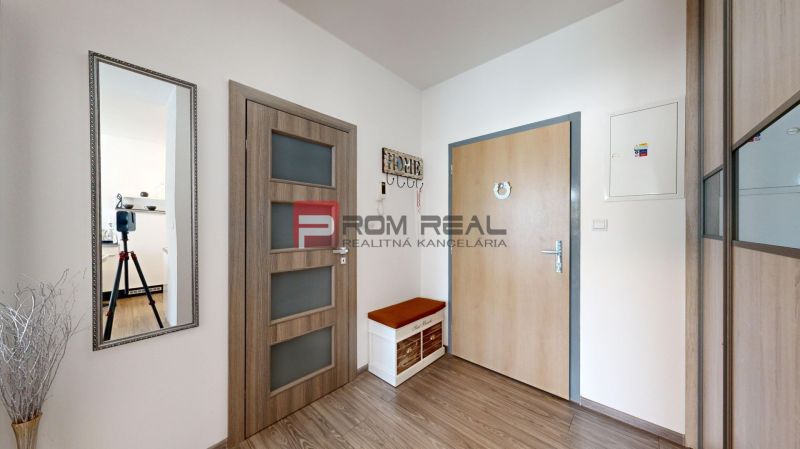 Interior of a 2-room apartment with a wooden decor floor and a mirror on the wall.