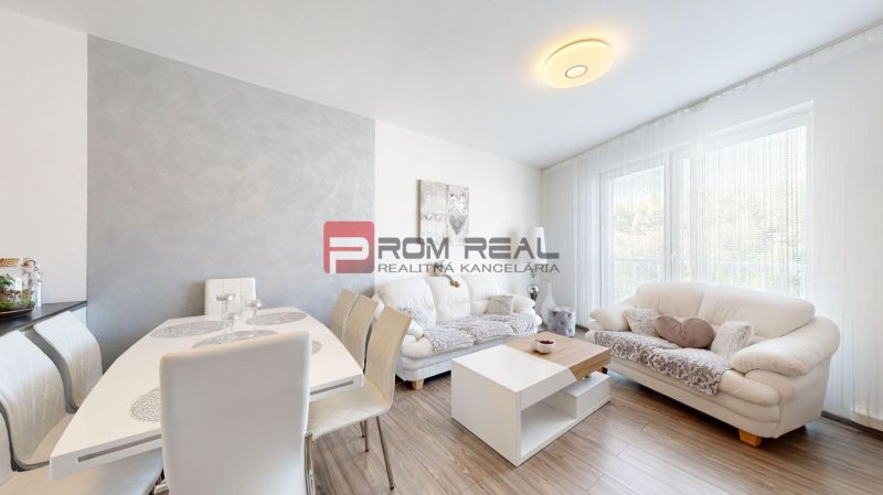 Living room in a two-room apartment with a wooden decor floor, light furniture, and a dining table.