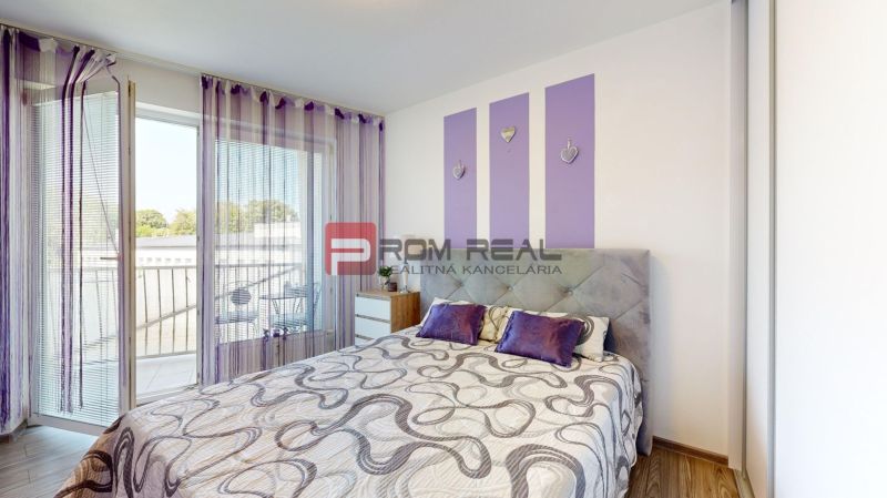 Bedroom in a two-room apartment with a bed, wardrobe, and purple decorations.
