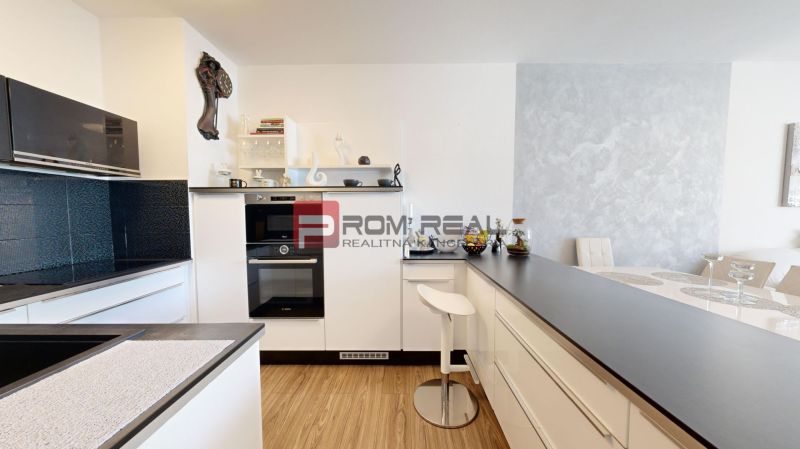 A kitchen in a 2-room apartment with black cabinets and a wooden-patterned floor.